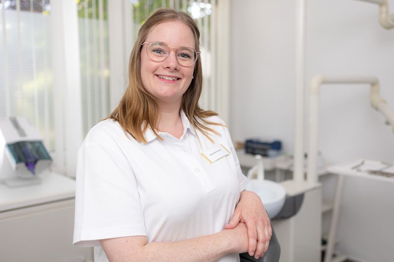 Eine Frau mit Brille und weißem Hemd lächelt in die Kamera.