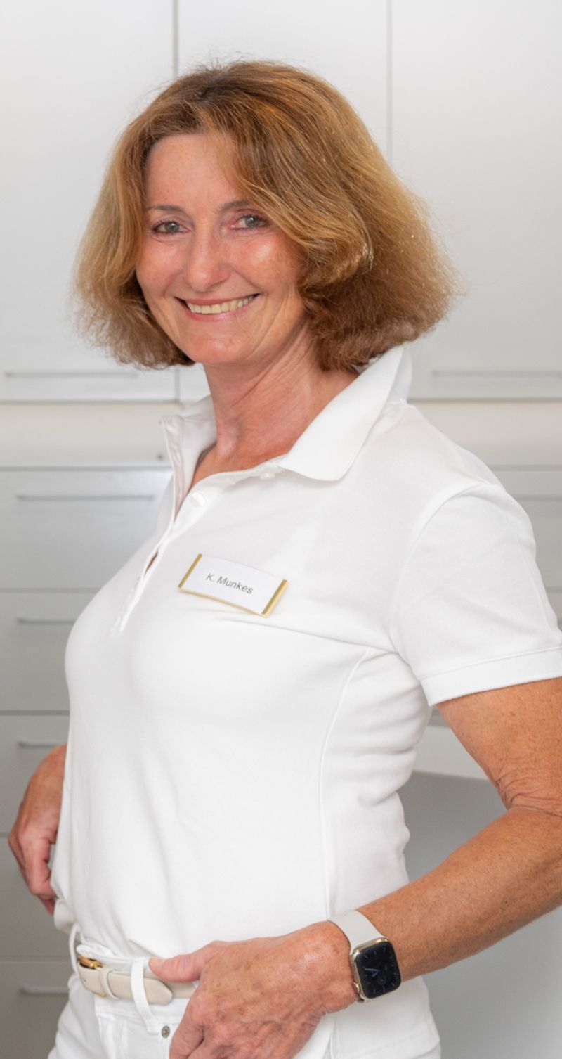 Eine Frau trägt ein weißes Poloshirt und lächelt.