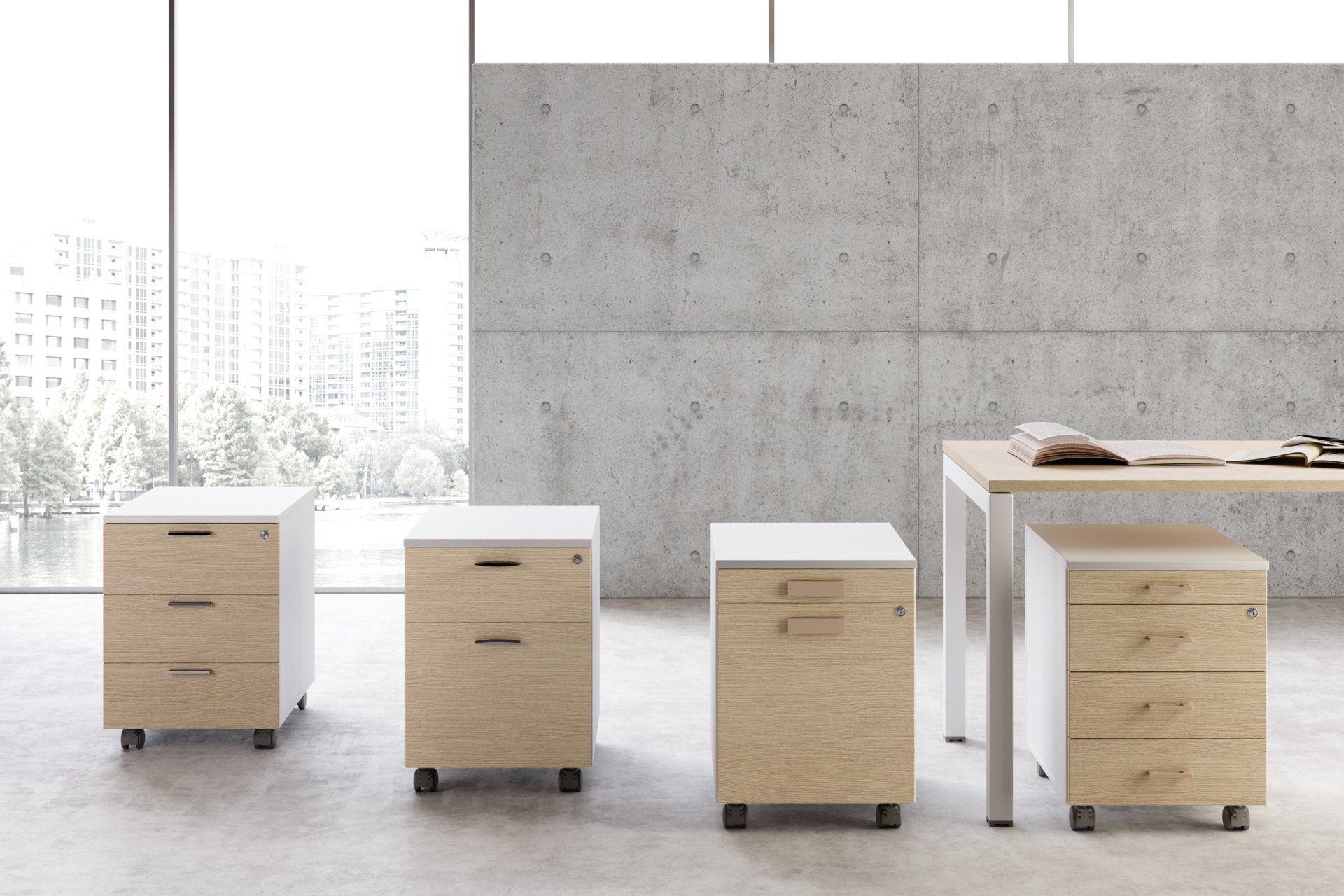 Quatre classeurs de bureau en bois, à couvercle blanc, montés sur roulettes et pieds, devant un mur en béton et une fenêtre.