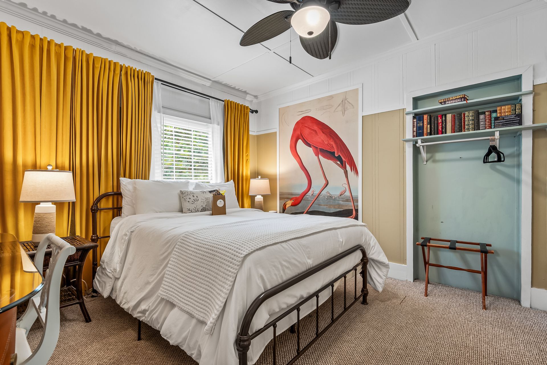 Bright Flamingo bedroom with white bed, yellow curtains, flamingo wall art, ceiling fan, and small desk nook