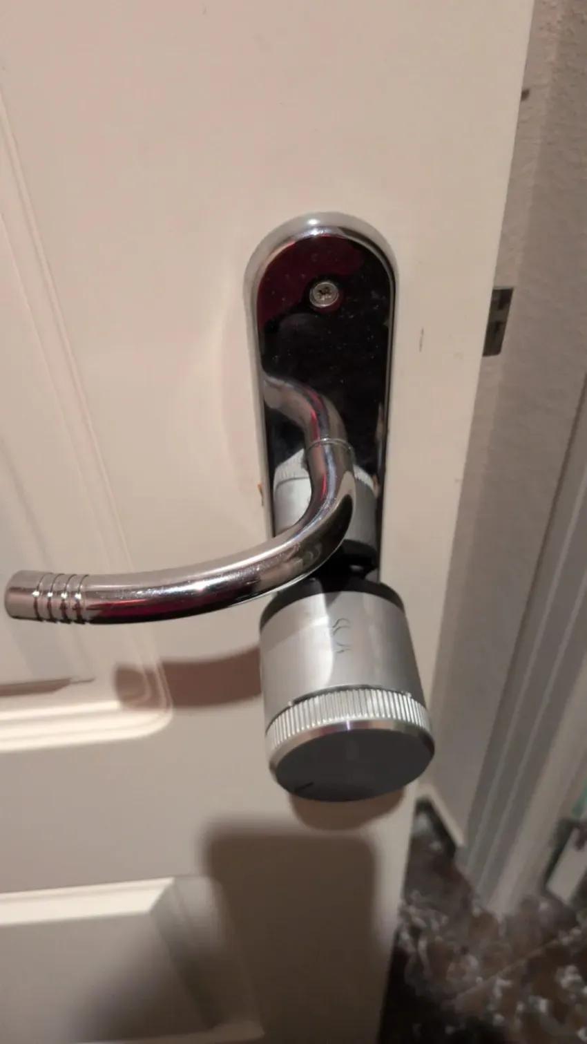Manilla cromada con cerradura en una puerta interior blanca.