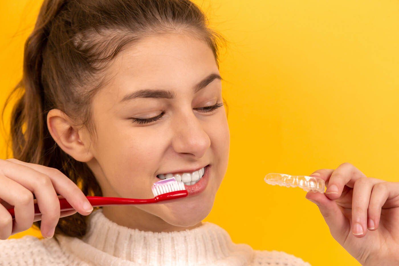 Fille se brossant les dents avec une prothèse dentaire à la main