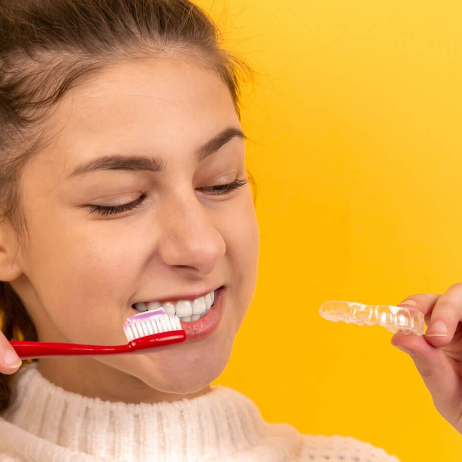 Fille se brossant les dents avec une prothèse dentaire à la main