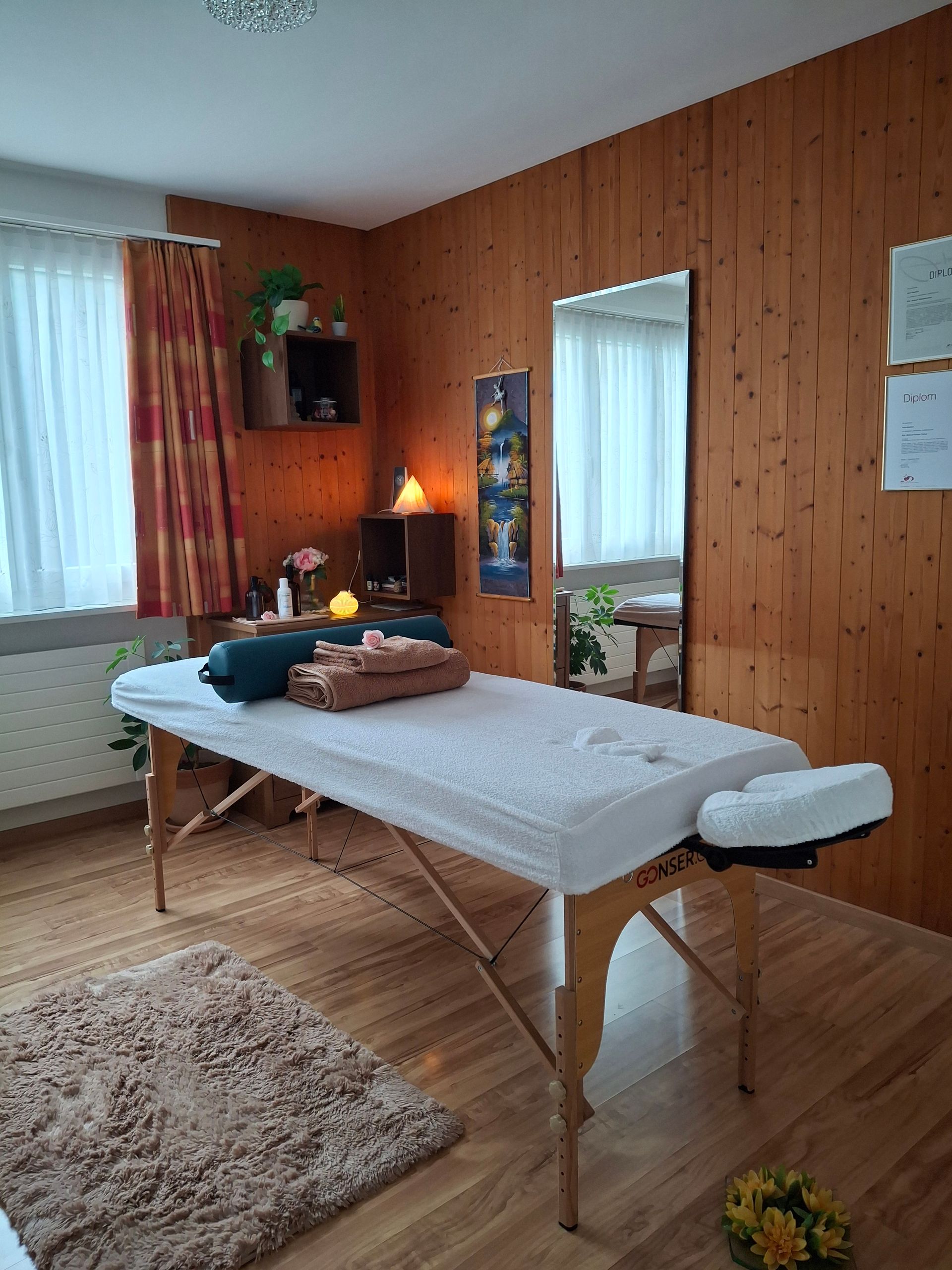 Hände, die eine Rückenmassage an einer auf einer Matte liegenden Person durchführen.