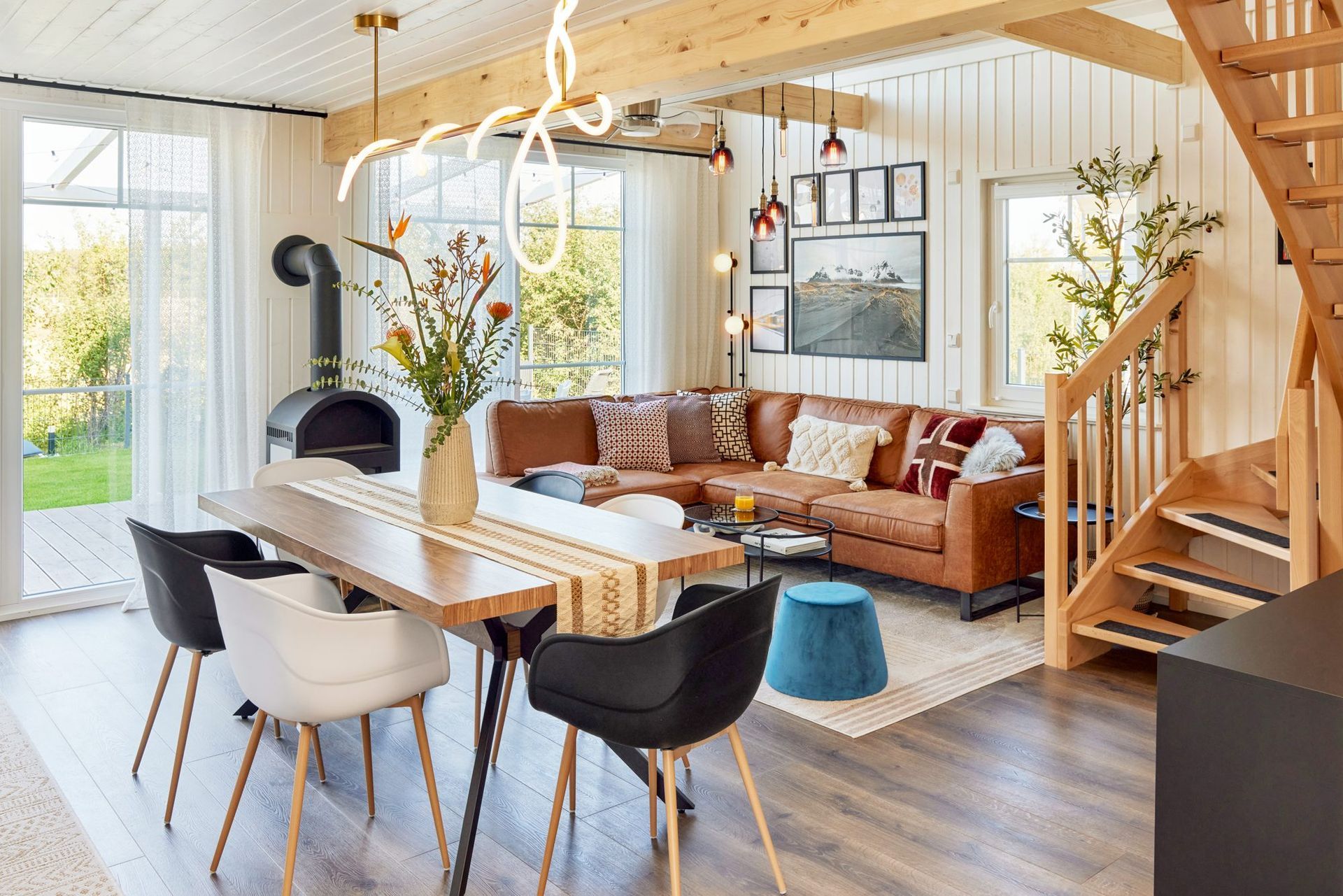 Open living and dining room with leather sofa, dining table and stairs
