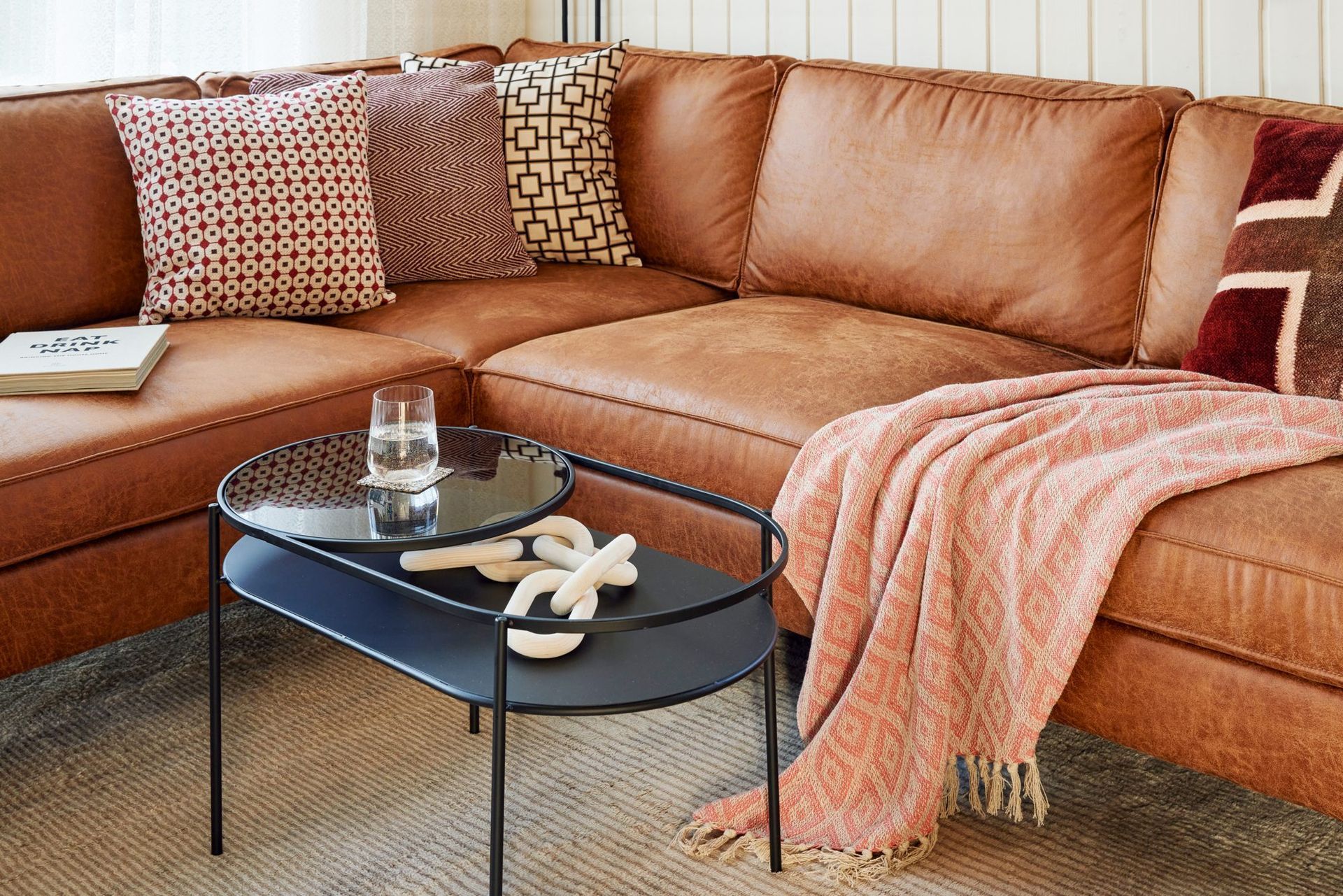 Leather corner sofa with a pink blanket and coffee table