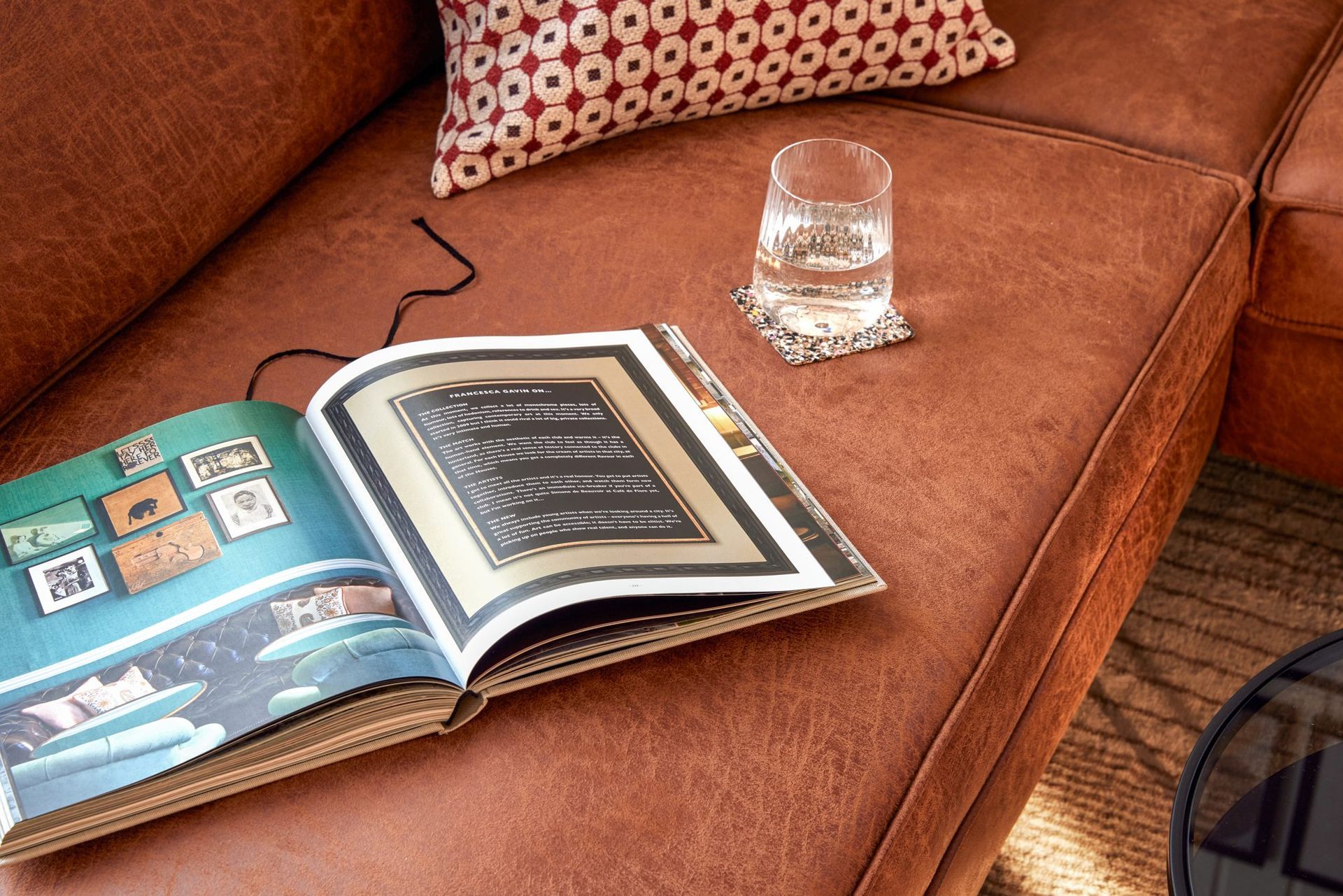 Open book and a glass of water on the leather sofa