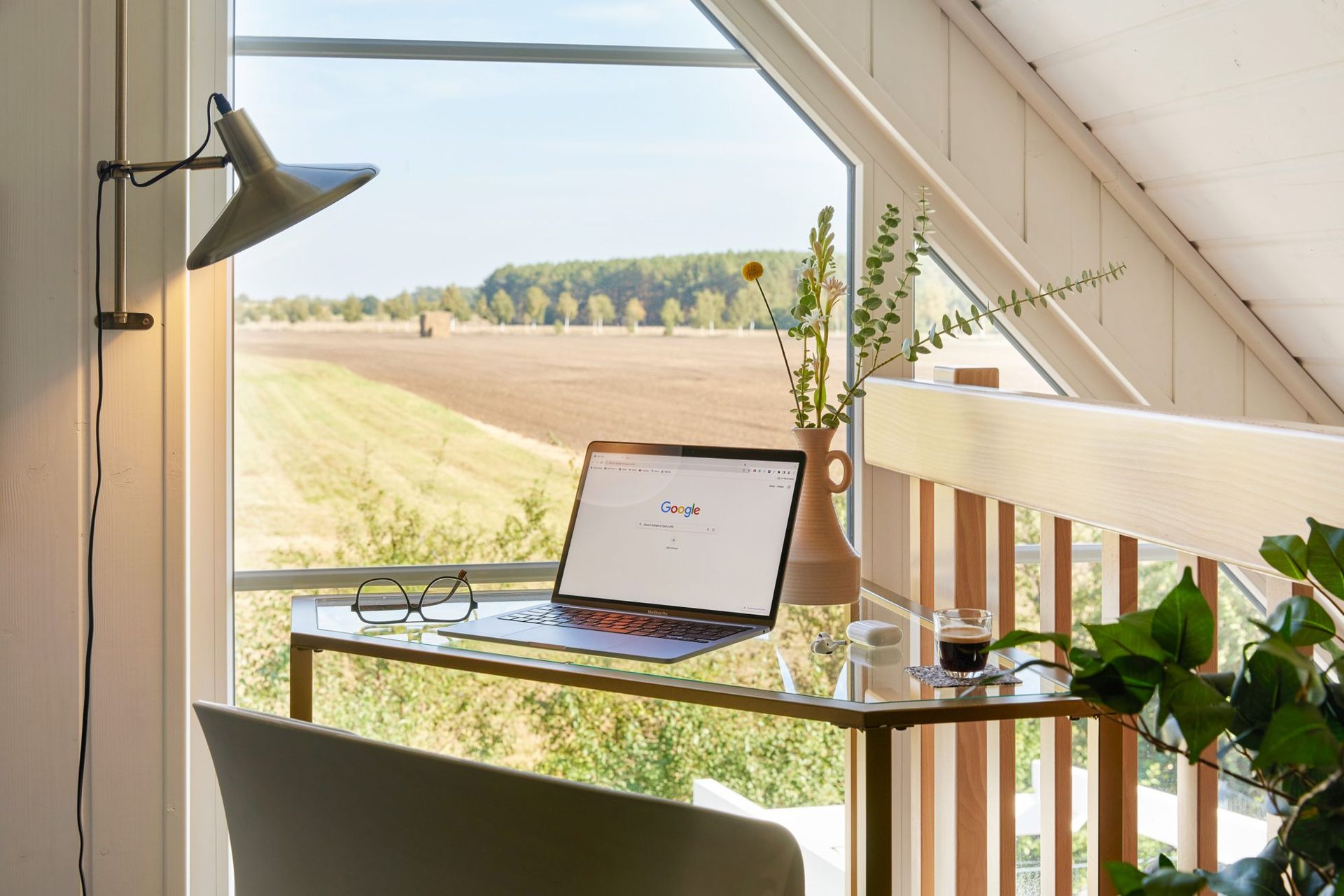 Desk with a laptop at a window overlooking open fields