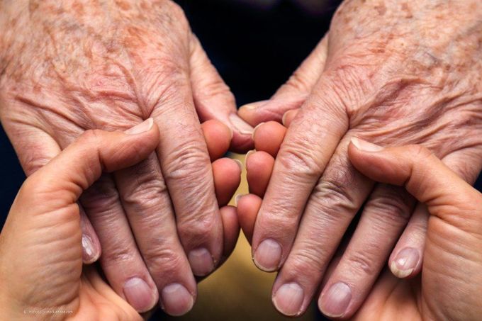 Zwei Frauenhände halten zwei Seniorenhände