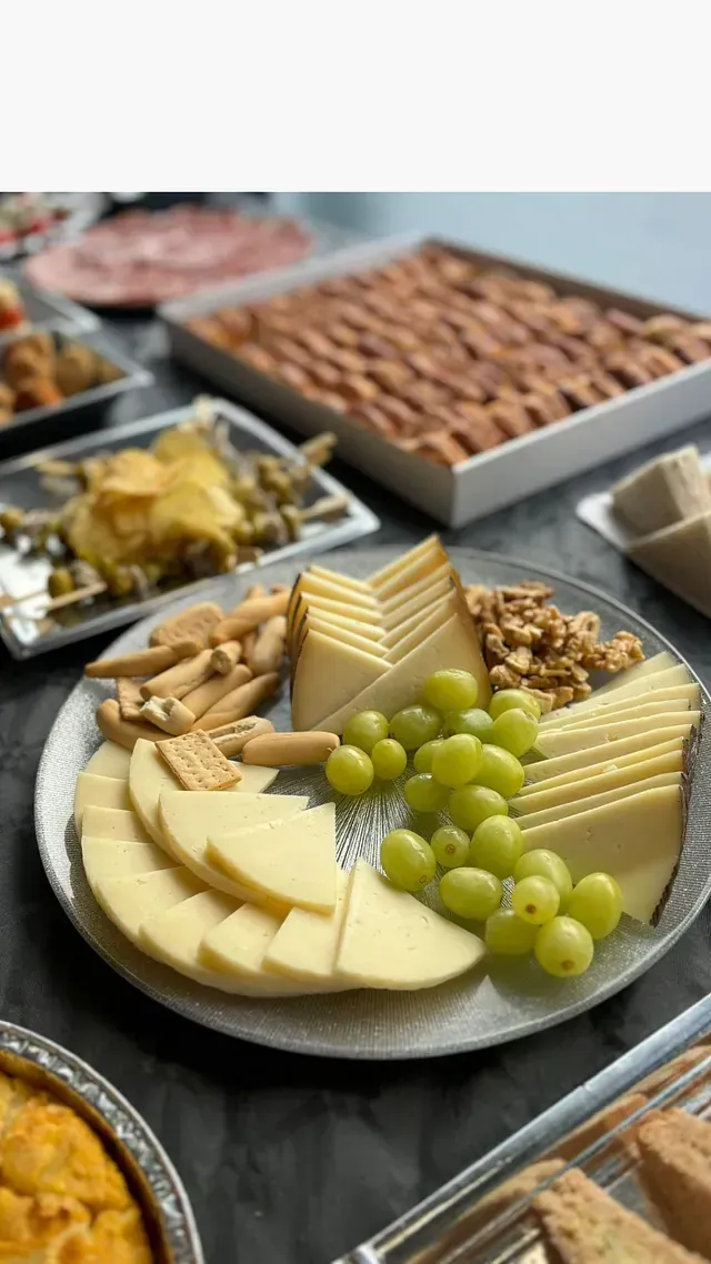 Un plato de queso, uvas, nueces y galletas en una mesa.