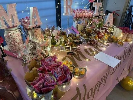 Una mesa decorada para una fiesta de cumpleaños con dulces, flores y globos.