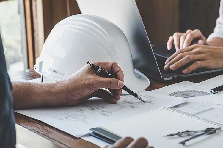 Un homme étudie un plan et une femme écrit sur un ordinateur