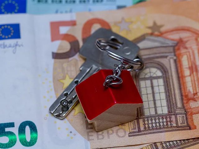 Llaves con un dije en forma de casa encima de un billete de 50 euros.