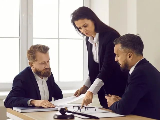 Tres profesionales revisando documentos en un escritorio en un entorno de oficina.