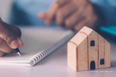 Modellhaus vor Person, die Notizen schreibt