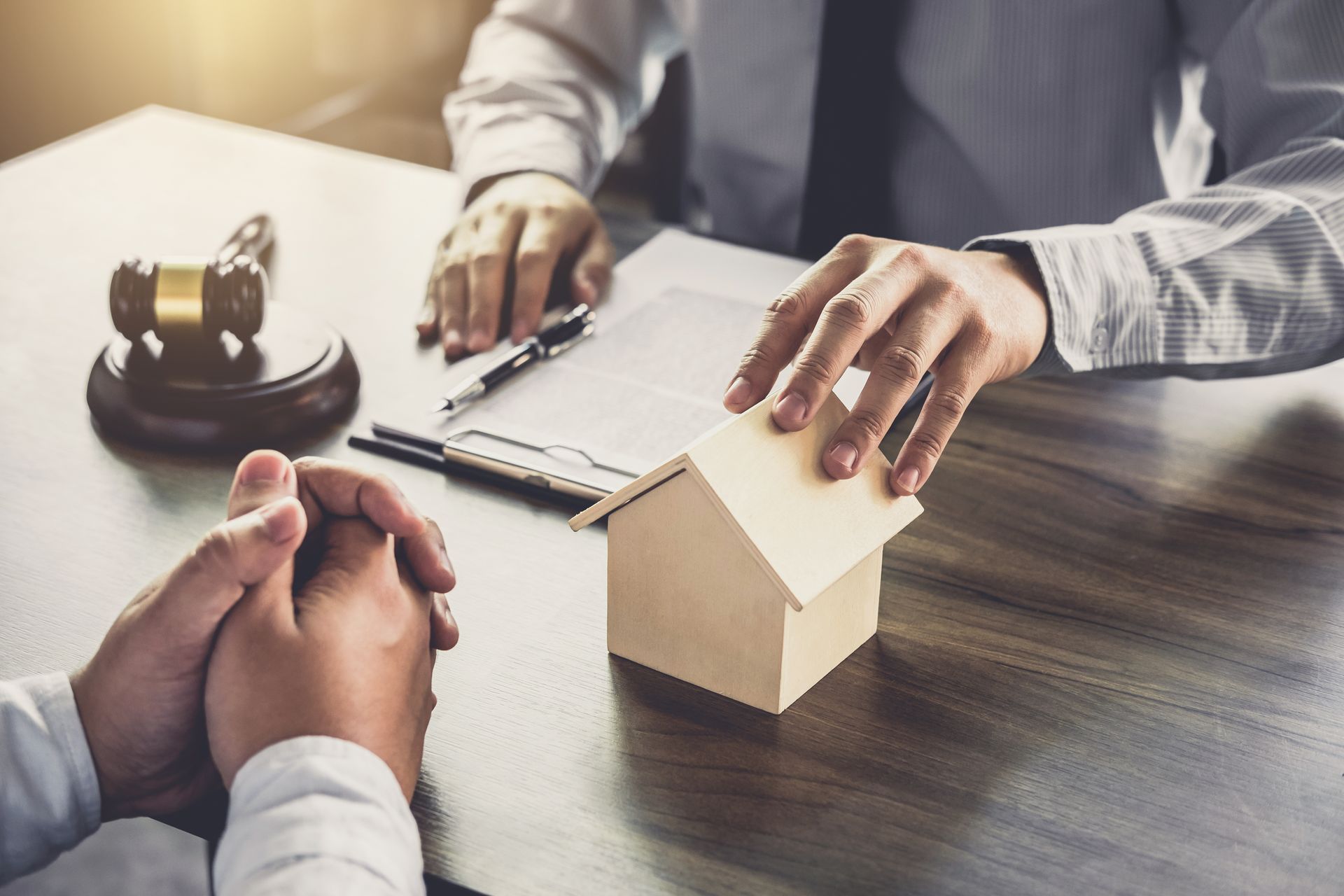 Un notaire et son client discutent, main posée sur une maison miniature