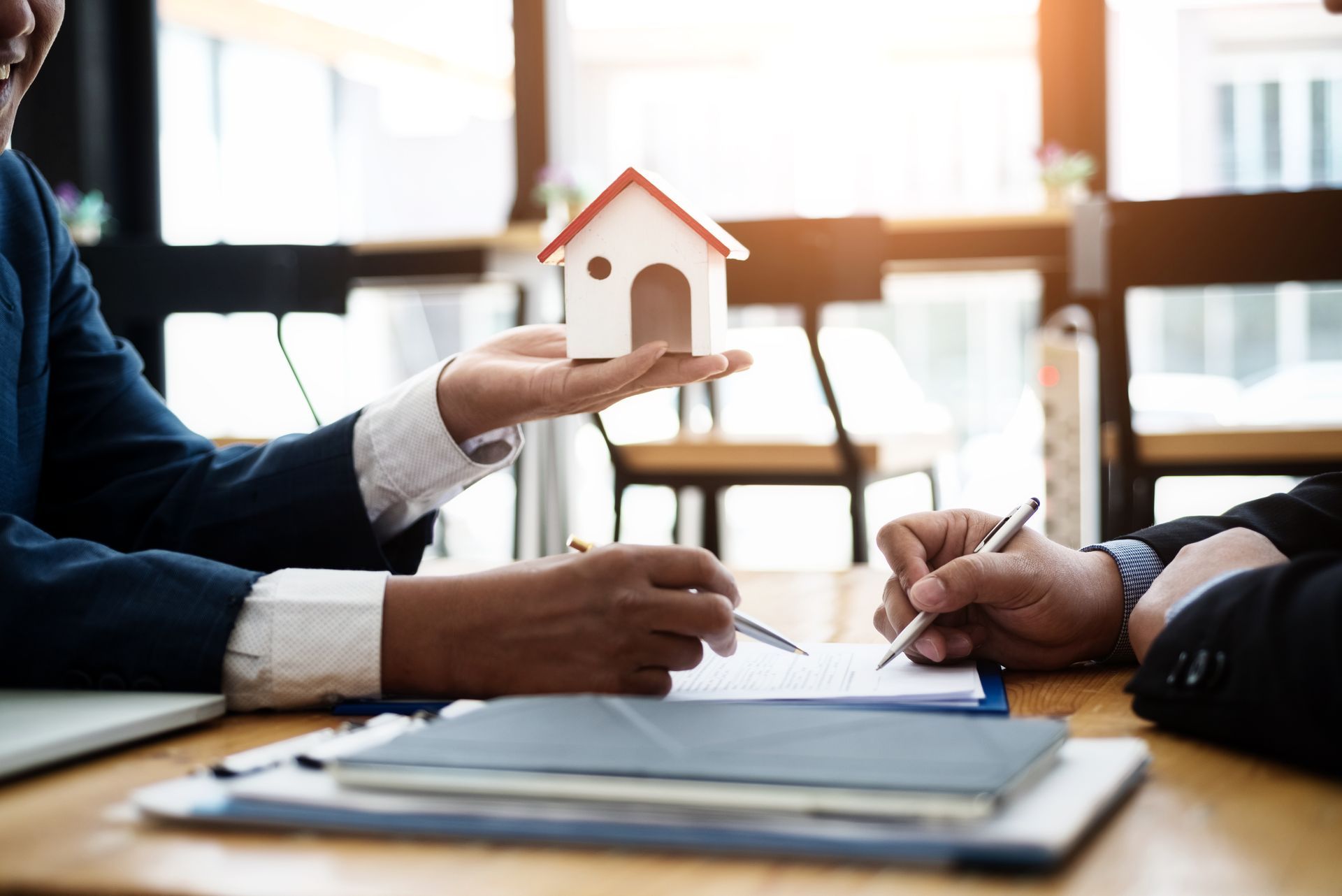 Main tenant une maison et une personne signant un document