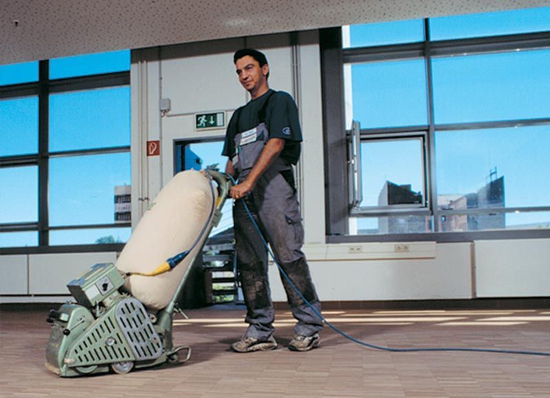 Ein Mann benutzt eine Maschine, um einen Boden zu schleifen