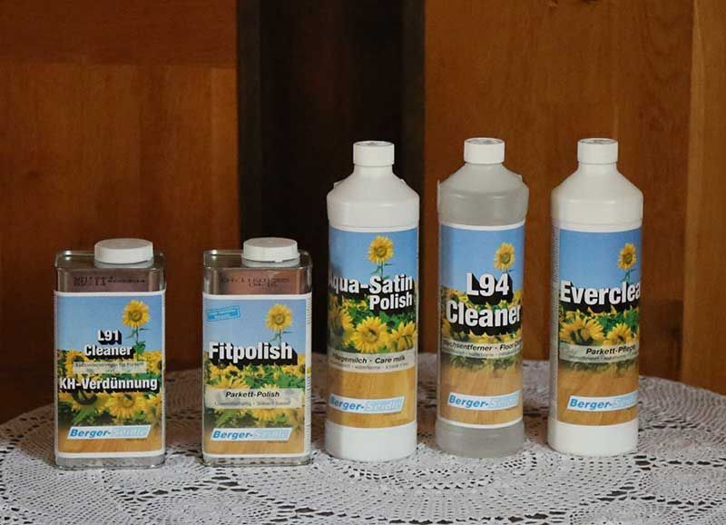 Fünf Flaschen mit Reinigungsmitteln stehen aufgereiht auf einem Tisch.