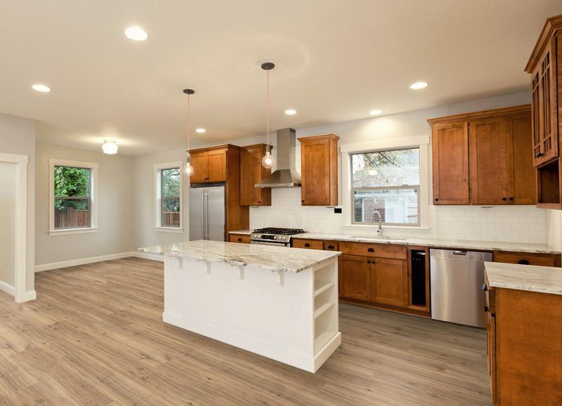 Eine Küche mit Holzschränken, Geräten aus Edelstahl und einer großen Kochinsel.