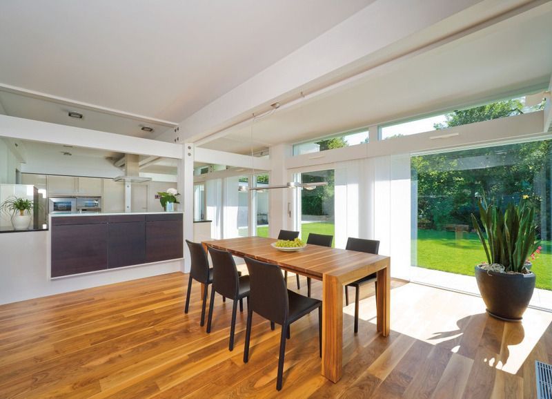 Ein Esszimmer mit einem Holztisch und Stühlen und einem großen Fenster.