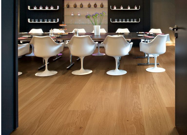 Ein Esszimmer mit Holzboden und weißen Stühlen