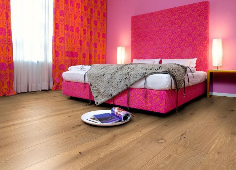 Ein Schlafzimmer mit rosa Vorhängen und einem Bett mit einer Zeitschrift auf dem Boden.