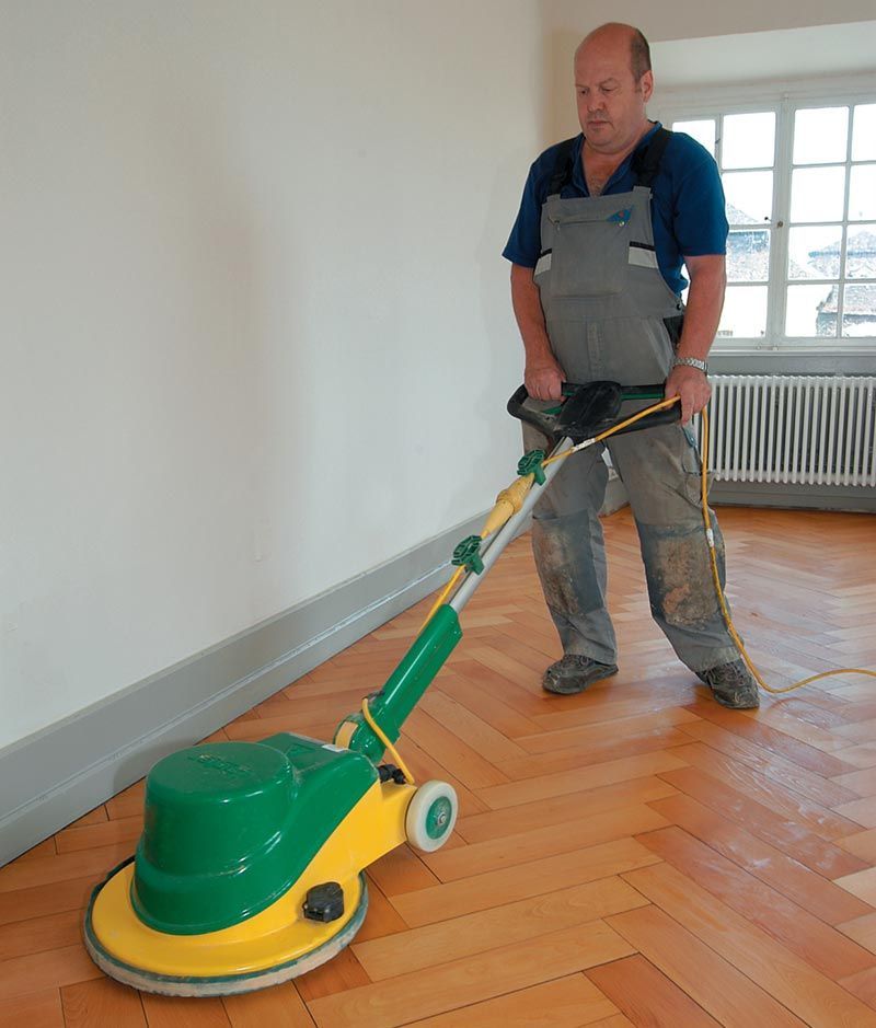 Ein Mann poliert mit einer Maschine einen Holzboden
