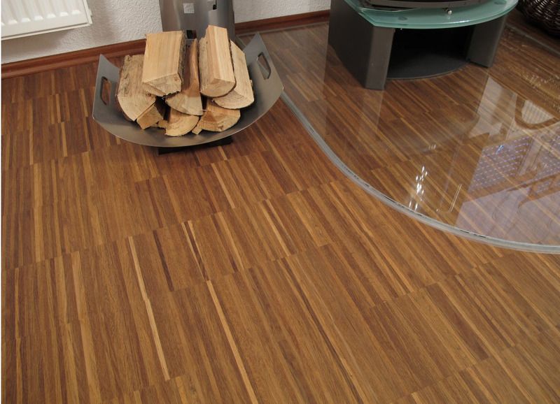 Ein Korb mit Holzscheiten steht auf einem Holzboden neben einem Glastisch