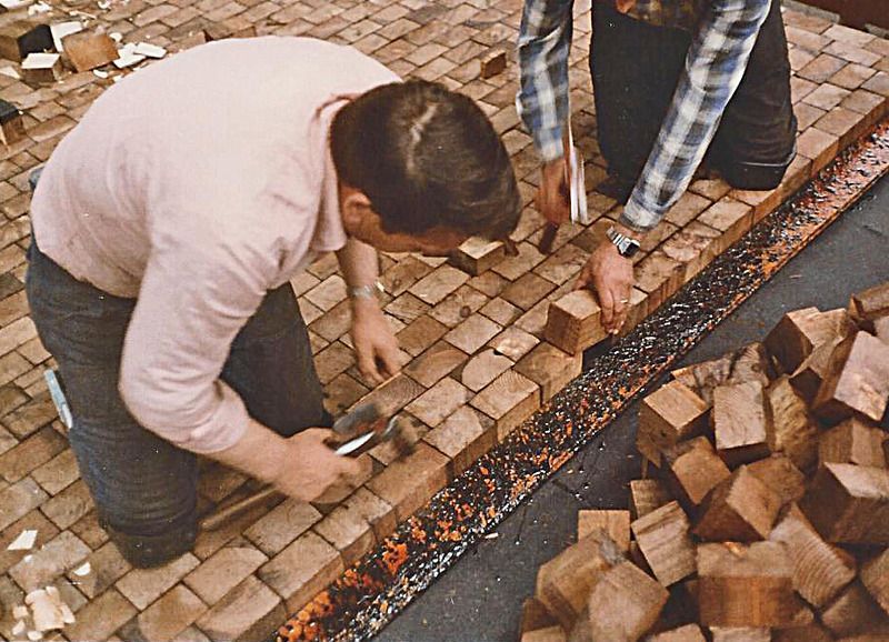 Ein Mann kniet nieder und hämmert mit einem Hammer auf ein Stück Holz.