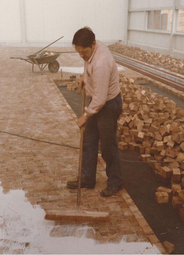 Ein Mann in einem rosa Hemd fegt Ziegelsteine mit einem Besen