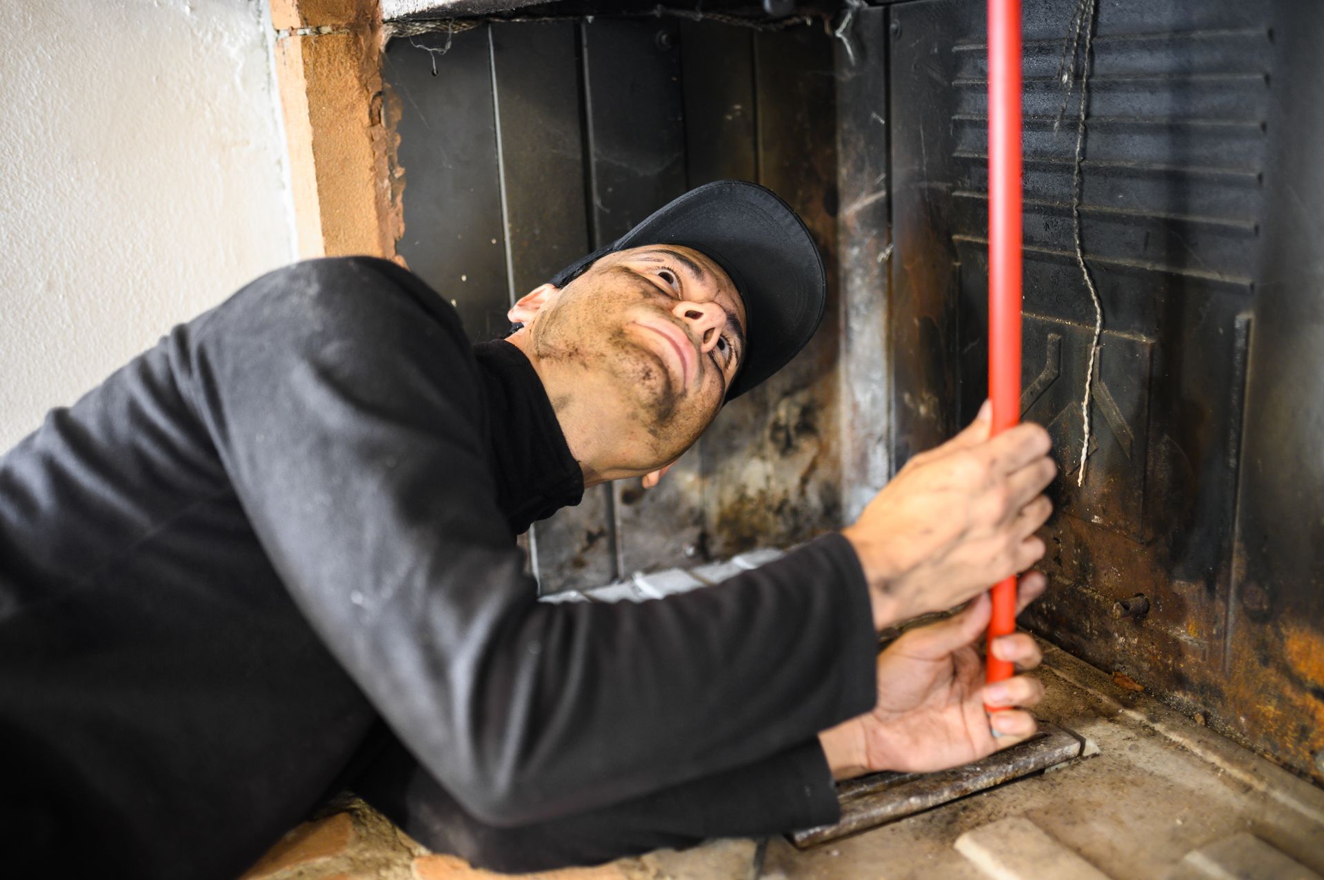 Un homme nettoie une cheminée avec un balai.