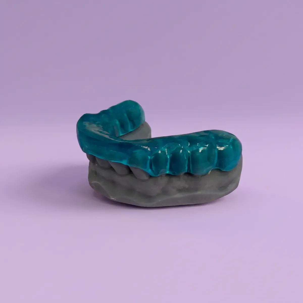 Protector bucal dental azul y gris sobre un fondo morado claro