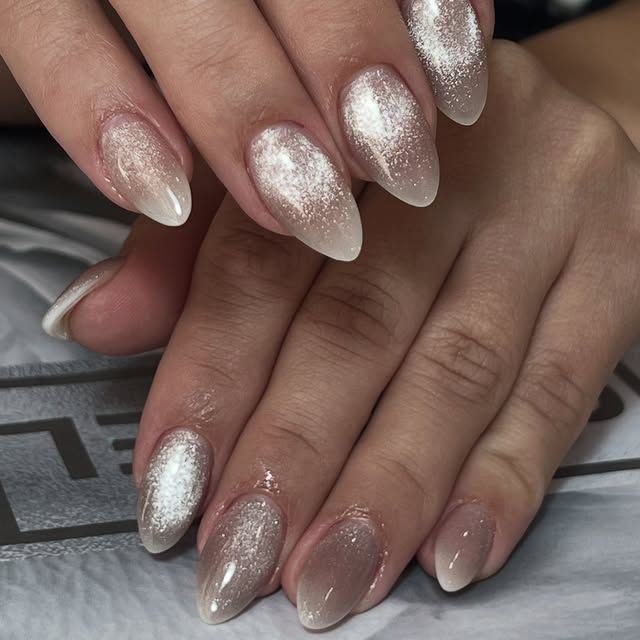 Primer plano de manos con uñas manicuradas en degradado de purpurina plateada.