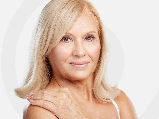 Retrato de una mujer rubia sonriente sobre un fondo claro.