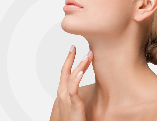 Mujer tocándose el cuello y la mandíbula sobre un fondo gris claro