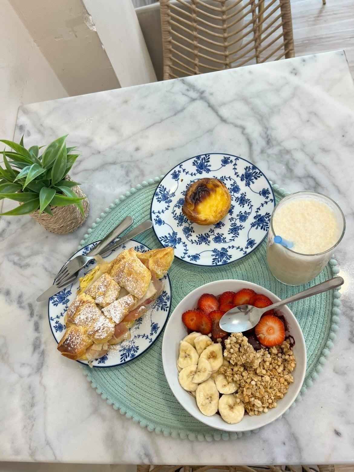 El desayuno, servido sobre una mesa de mármol, incluía fruta, bollería, yogur, granola y café en platos decorados con motivos florales.