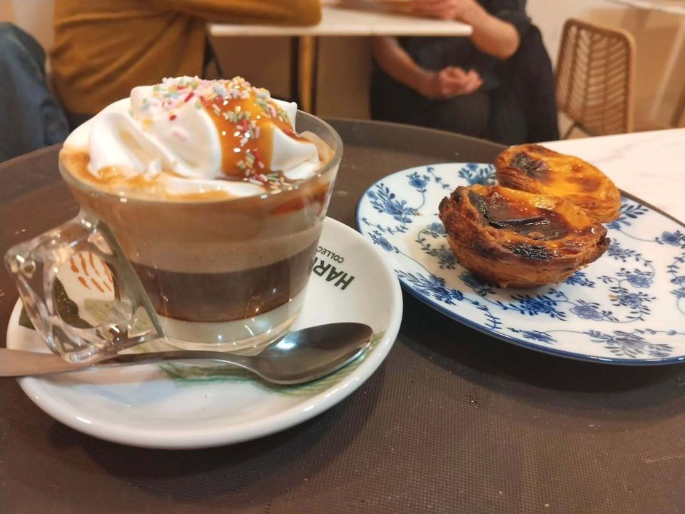 Café helado en capas y un pastel en una mesa con platos azules y blancos.