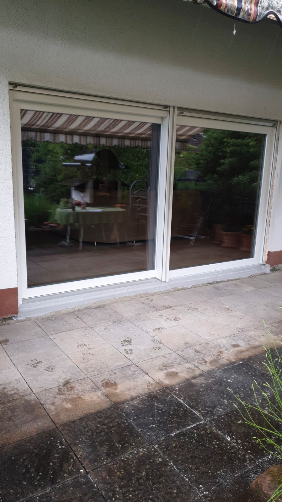 Eine Terrasse mit Glasschiebetür und gestreifter Markise.