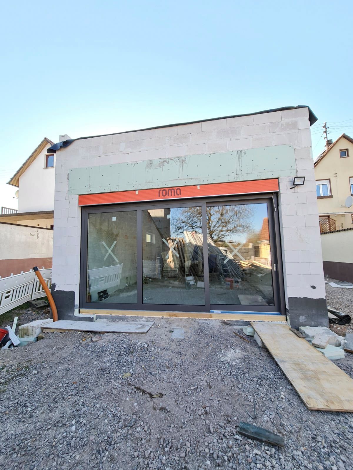 Es wird ein Gebäude mit vielen Fenstern und Glasschiebetüren gebaut.