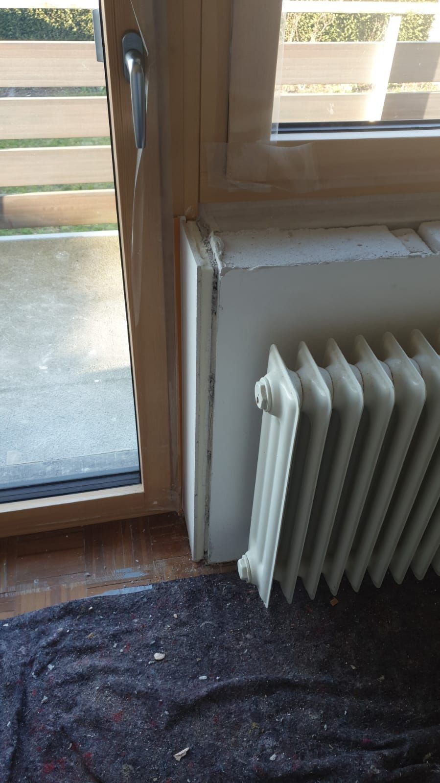 Ein Heizkörper steht neben einem Fenster in einem Zimmer.