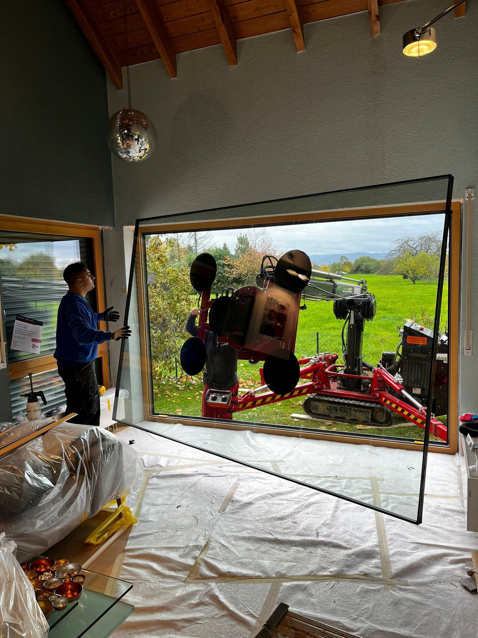 Ein Mann bearbeitet mit einer Maschine ein großes Fenster.
