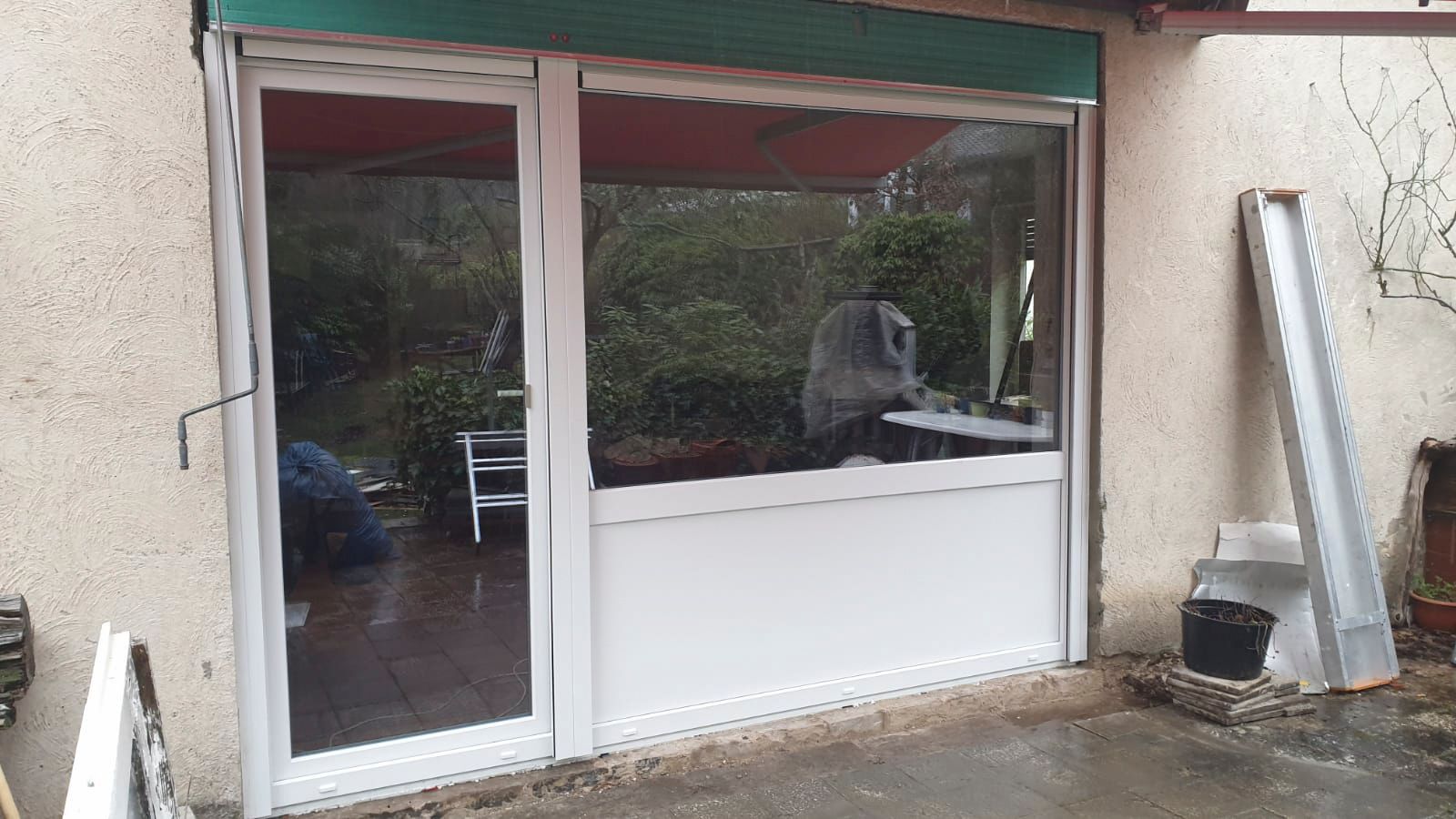 An der Seite eines Gebäudes befindet sich eine weiße Tür mit einem grünen Fensterladen.