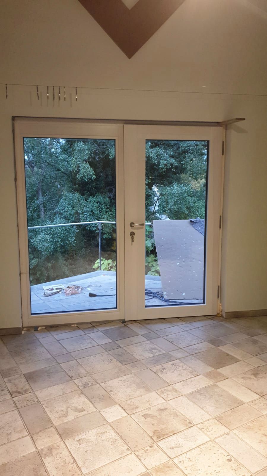 Ein leerer Raum mit einer Glasschiebetür und gefliestem Boden.