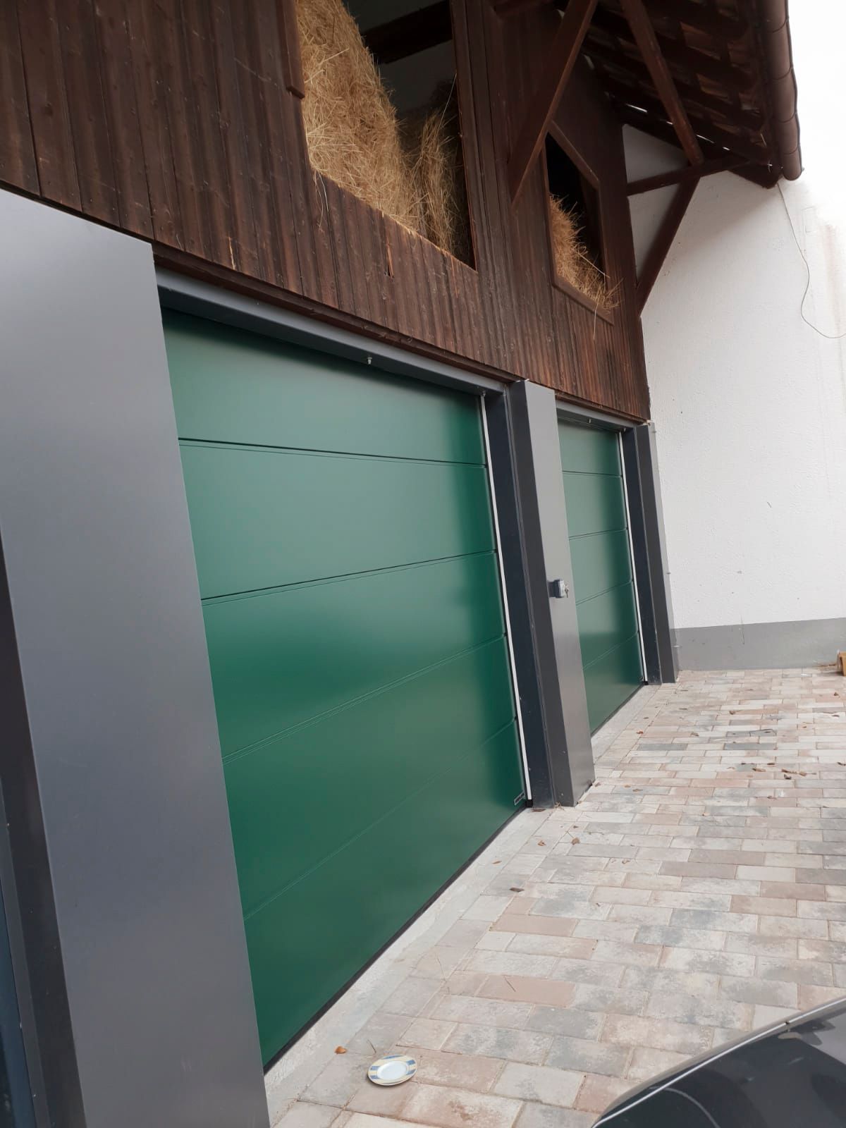 Eine Garage mit grünen Türen und einem davor geparkten Auto.