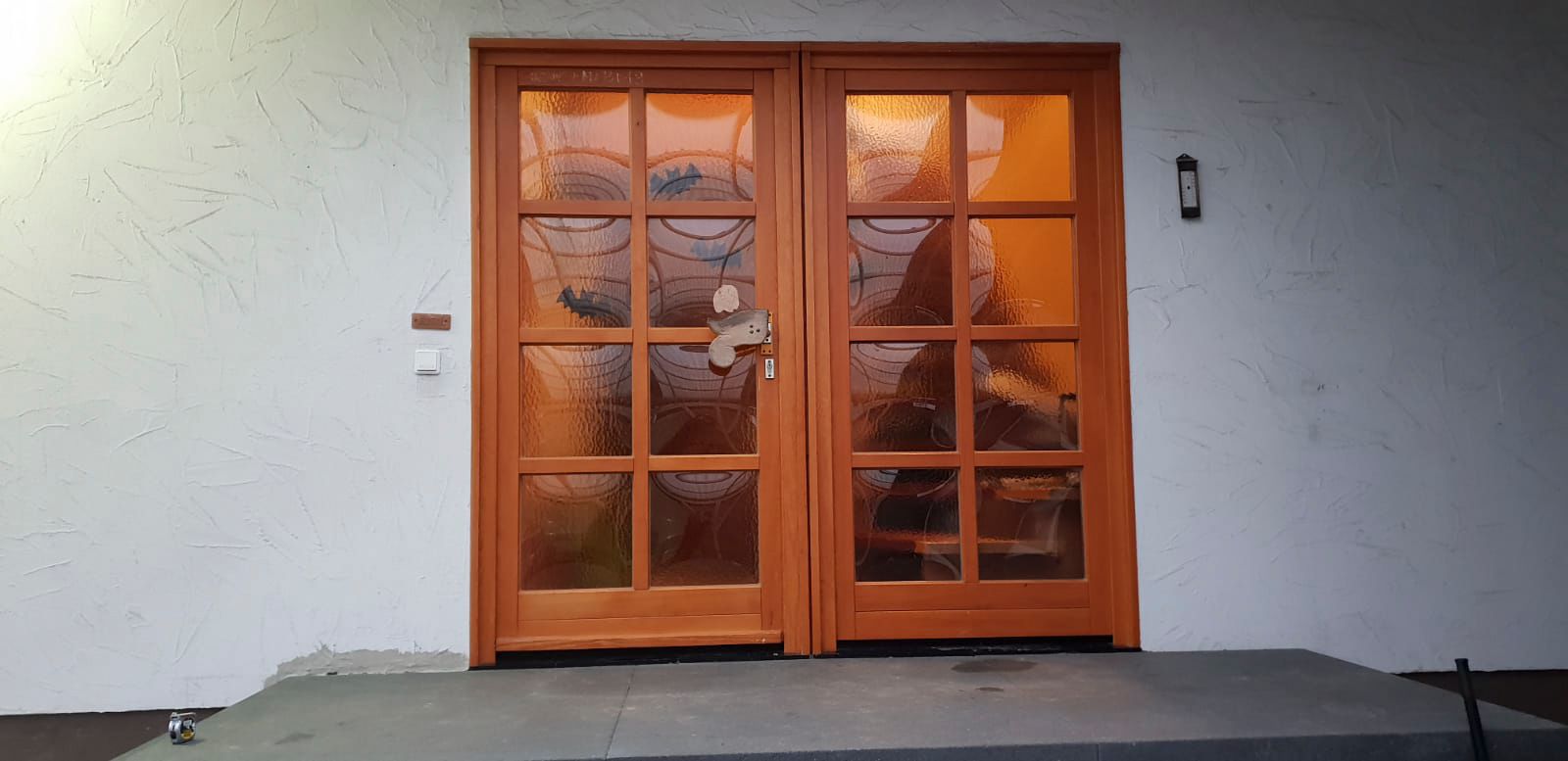 Auf einer Veranda steht eine Holztür mit vielen Fenstern.