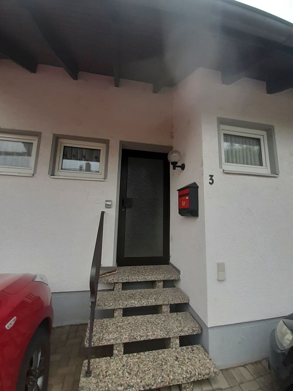 Ein weißes Haus mit einem davor geparkten roten Auto