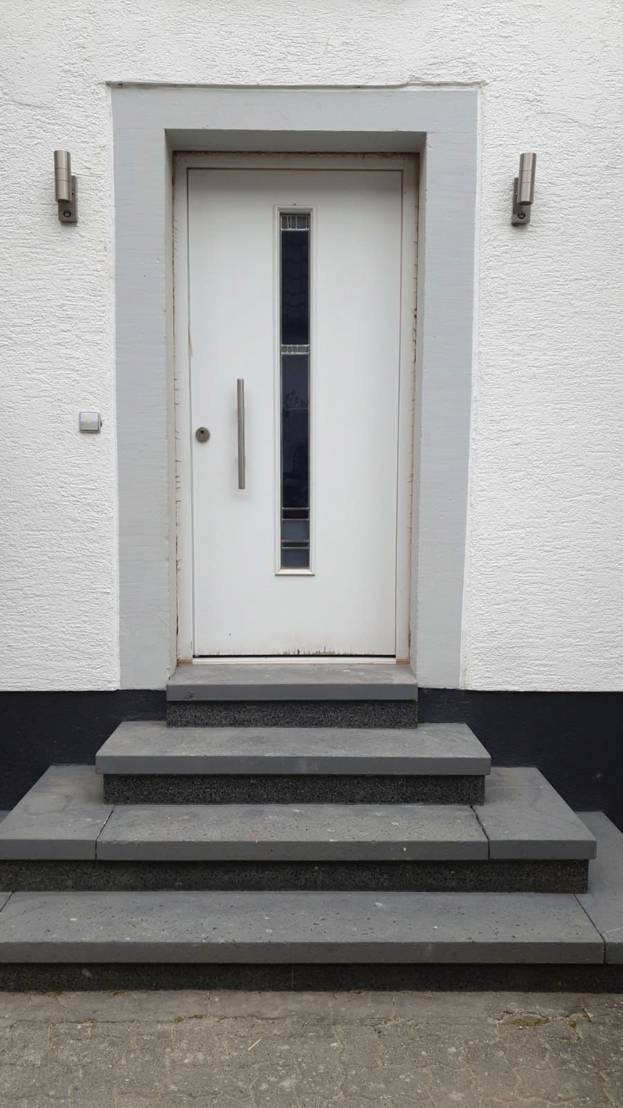 Eine weiße Tür an der Seite eines Gebäudes, zu der Stufen hinaufführen.