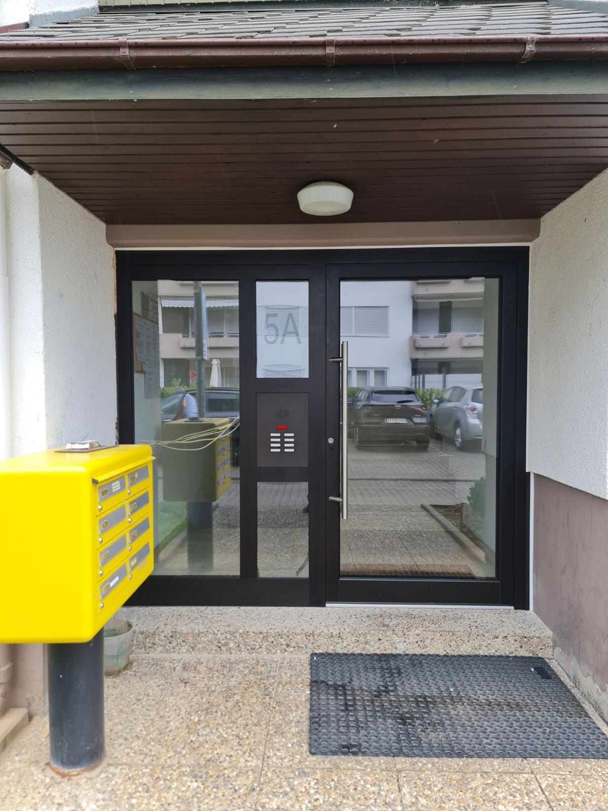 Ein gelber Briefkasten steht vor einer Tür mit der Aufschrift 5a