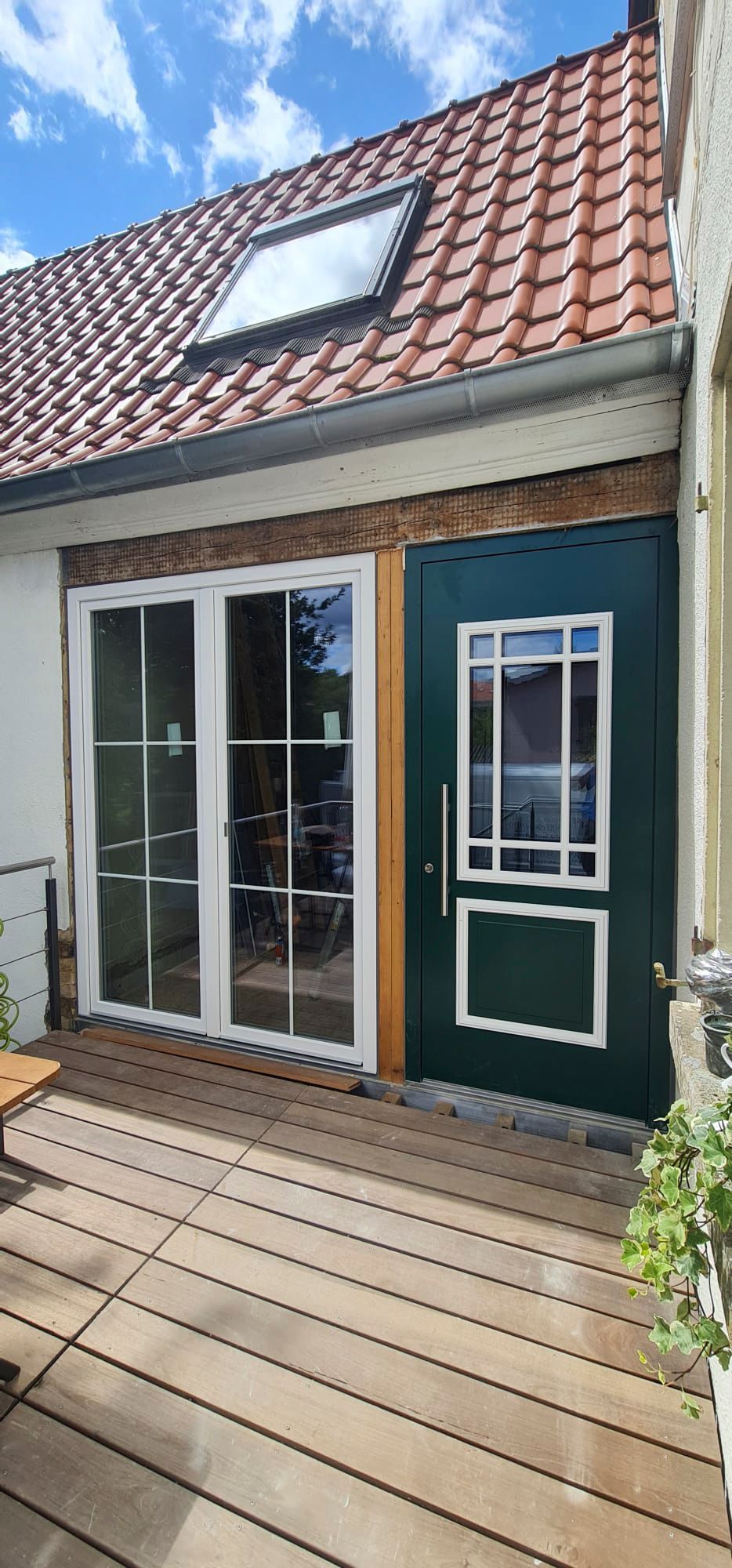 Ein Haus mit einer grünen Tür und einer Holzterrasse davor.